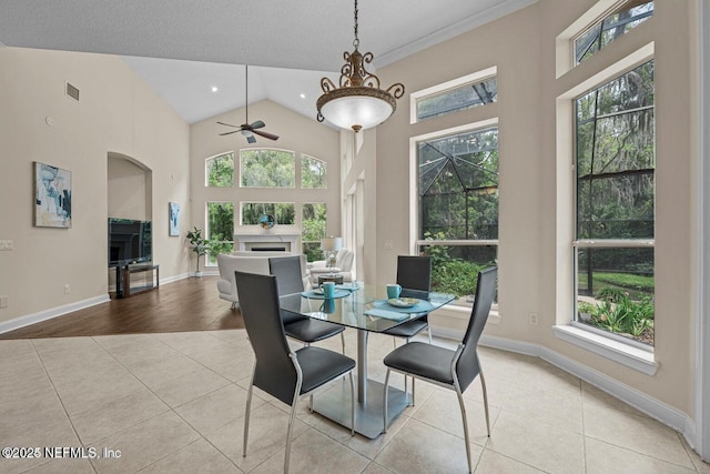 dining space with ceiling fan, light tile patterned floors, and high vaulted ceiling