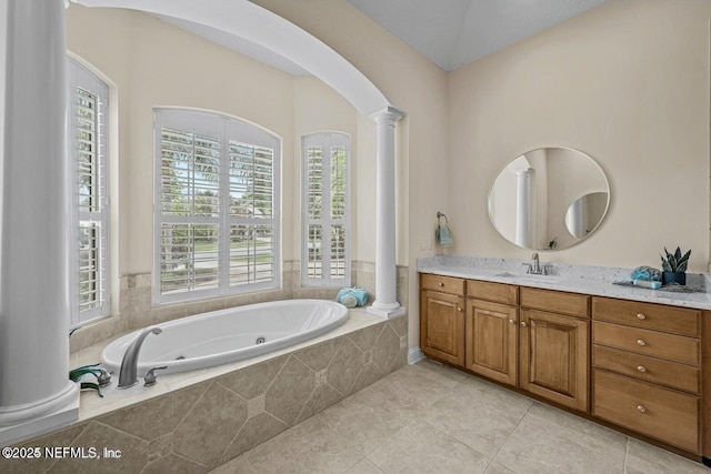 bathroom with tiled tub, tile patterned floors, vanity, and ornate columns