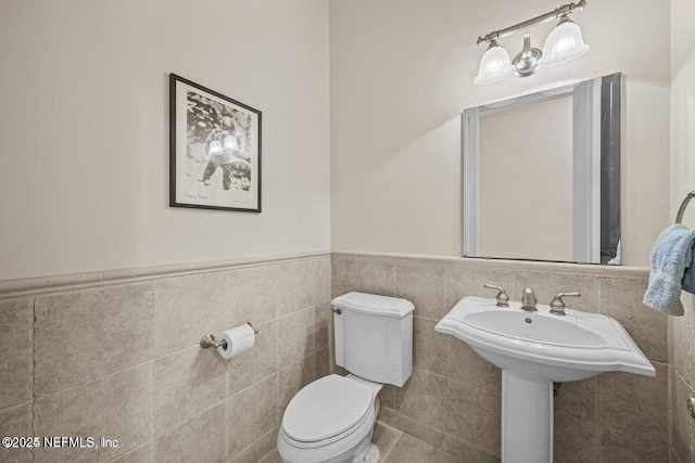 bathroom with toilet and tile walls