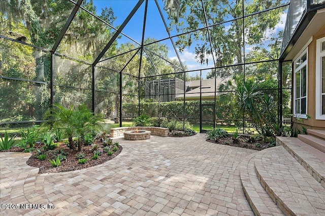 view of patio featuring glass enclosure and an outdoor fire pit