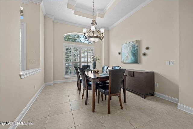 dining room with a textured ceiling, a tray ceiling, ornamental molding, a notable chandelier, and light tile patterned floors