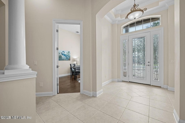 tiled entrance foyer featuring a high ceiling, crown molding, and ornate columns