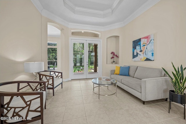 tiled living room with crown molding, a tray ceiling, and french doors