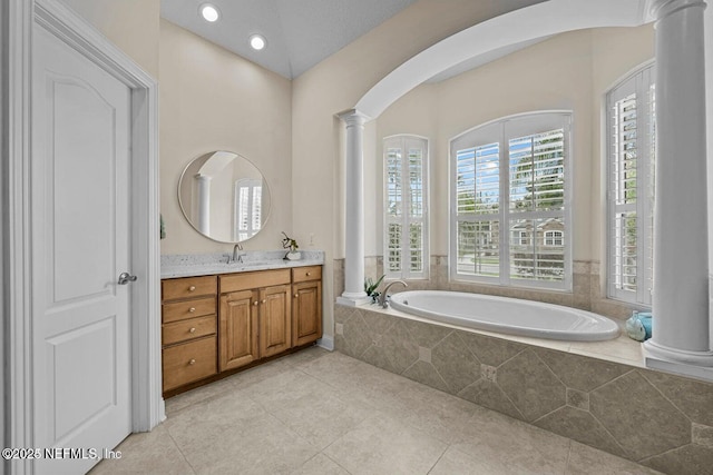 bathroom featuring decorative columns, tiled bath, vanity, and tile patterned flooring