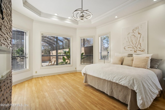 bedroom featuring a notable chandelier, a tray ceiling, ornamental molding, and hardwood / wood-style flooring