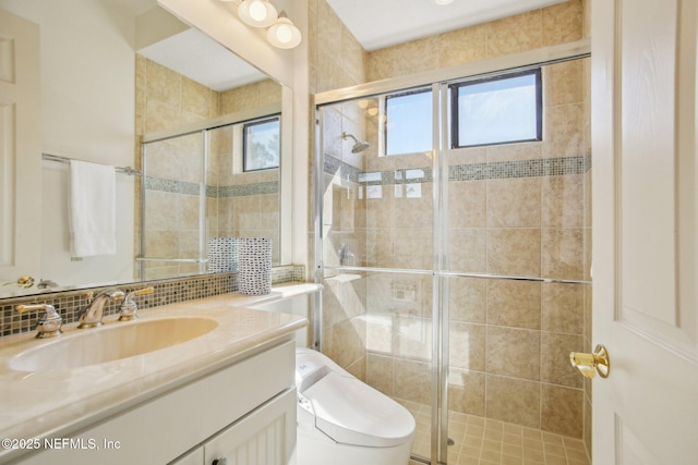 bathroom featuring vanity, backsplash, a shower with door, and toilet