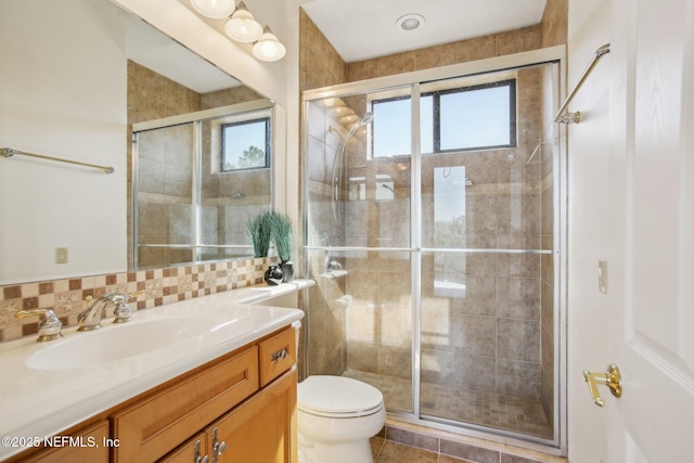 bathroom with vanity, backsplash, a shower with door, and toilet