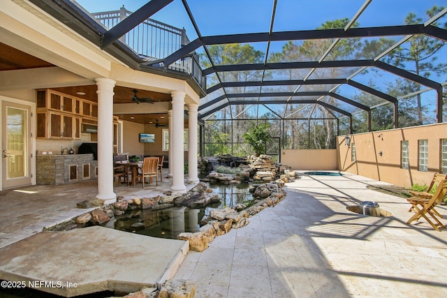 view of patio with ceiling fan, an outdoor kitchen, and a lanai