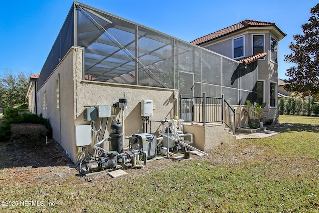 view of side of property featuring a lanai and a lawn