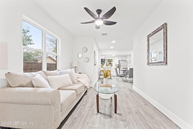 living room featuring light wood-type flooring, ceiling fan, and a wealth of natural light