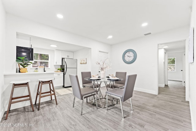 dining area featuring sink, light hardwood / wood-style flooring, and a wealth of natural light