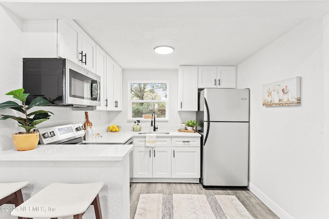 kitchen with white cabinets, appliances with stainless steel finishes, sink, and a breakfast bar area