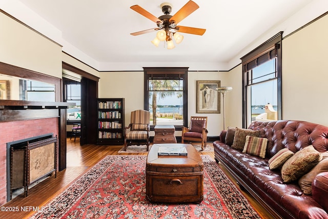 living room featuring hardwood / wood-style flooring, ceiling fan, and a fireplace