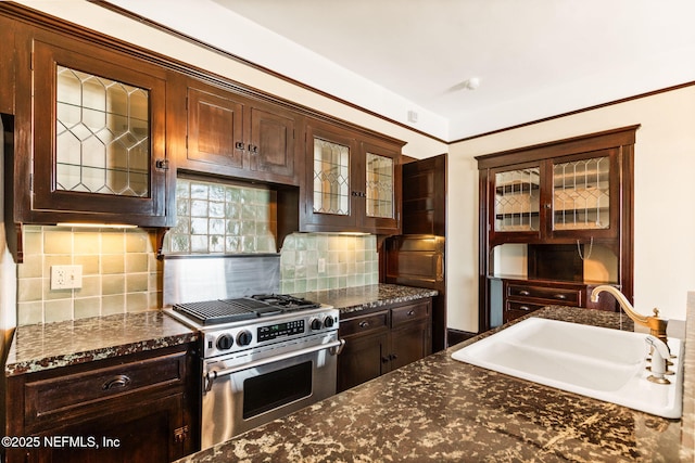 kitchen with dark stone counters, sink, dark brown cabinetry, stainless steel range with gas stovetop, and backsplash