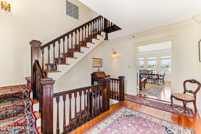 stairway with hardwood / wood-style flooring and ornamental molding