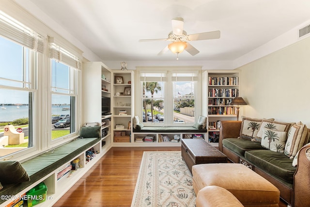 living area featuring hardwood / wood-style flooring, a water view, and ceiling fan