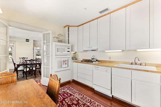 kitchen with sink, white appliances, white cabinets, and dark hardwood / wood-style flooring