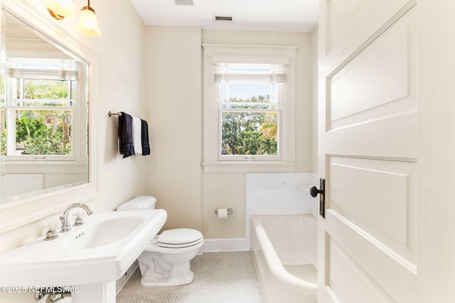 bathroom featuring a bath, toilet, and sink