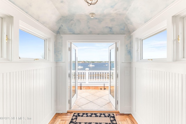 doorway to outside with a water view, light parquet flooring, and lofted ceiling