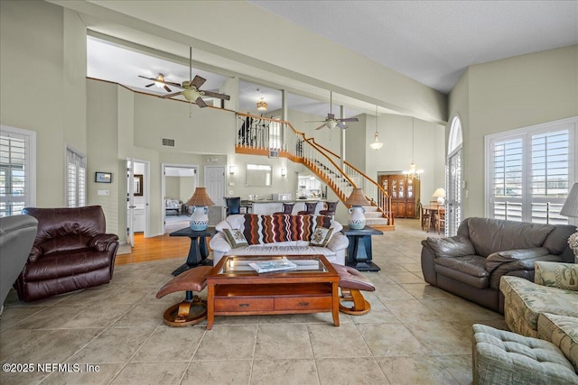 living room with ceiling fan with notable chandelier and a high ceiling