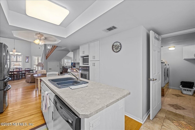 kitchen with sink, washer and dryer, appliances with stainless steel finishes, a kitchen island, and white cabinets