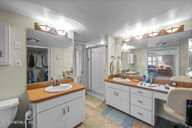 bathroom featuring a shower with door, vanity, tile patterned floors, and toilet