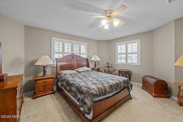 bedroom with ceiling fan, light colored carpet, and a textured ceiling