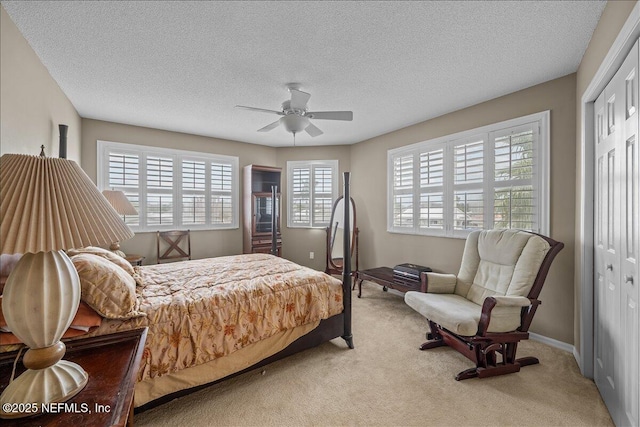 bedroom with multiple windows, light colored carpet, a closet, and ceiling fan