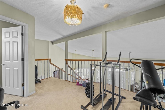 exercise area featuring lofted ceiling, carpet flooring, a textured ceiling, and an inviting chandelier