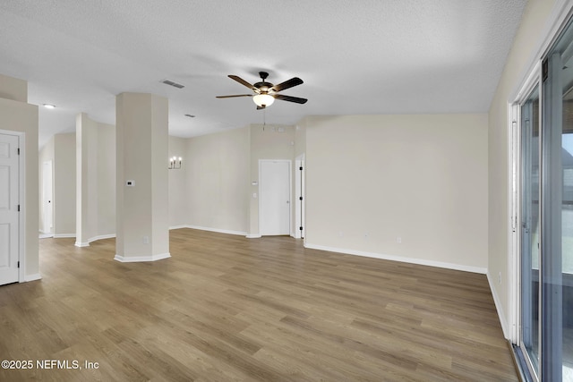 spare room featuring a textured ceiling, light hardwood / wood-style floors, and ceiling fan with notable chandelier