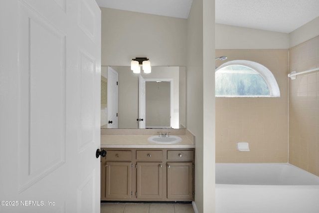 bathroom featuring tile patterned flooring, tiled shower / bath combo, vanity, and vaulted ceiling