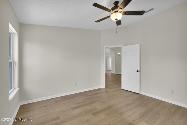 empty room with ceiling fan, a textured ceiling, a healthy amount of sunlight, and light wood-type flooring