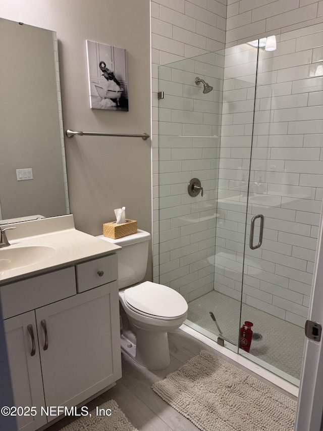 bathroom featuring wood-type flooring, toilet, walk in shower, and vanity