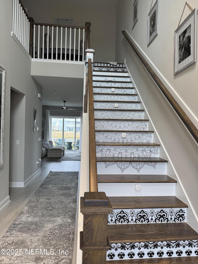 stairs featuring hardwood / wood-style floors and a towering ceiling