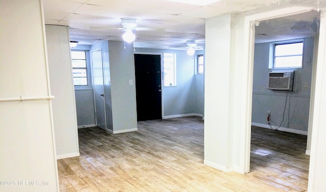 corridor with light hardwood / wood-style floors, cooling unit, and plenty of natural light