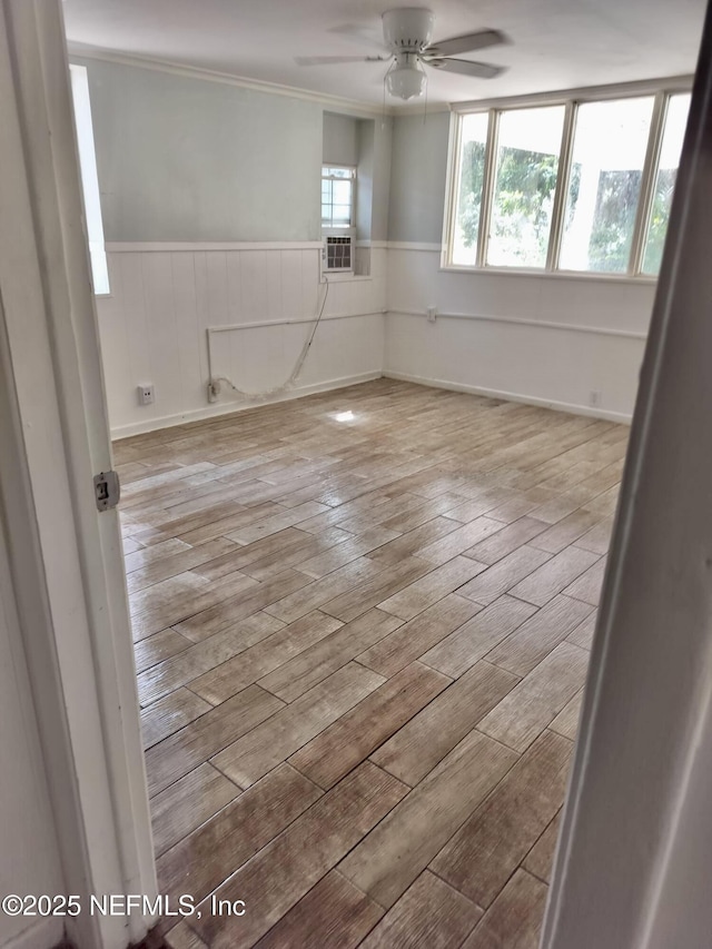 empty room featuring ceiling fan, cooling unit, and light hardwood / wood-style flooring