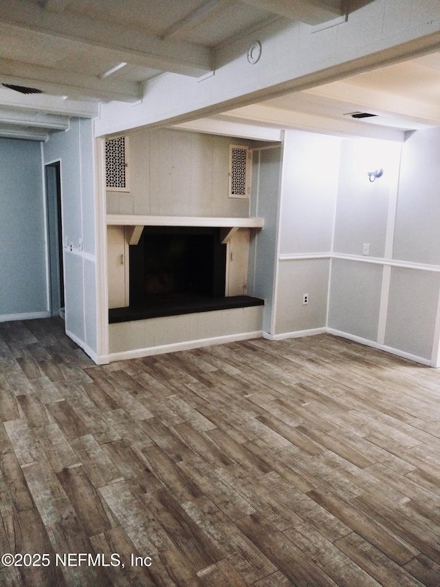 unfurnished living room featuring hardwood / wood-style flooring, a tile fireplace, and beam ceiling