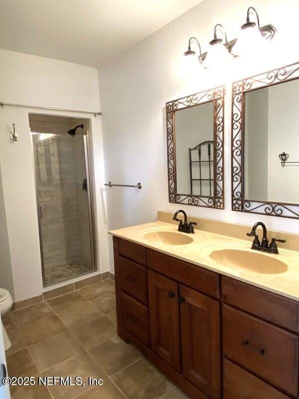 bathroom with a shower with door, vanity, tile patterned flooring, and toilet