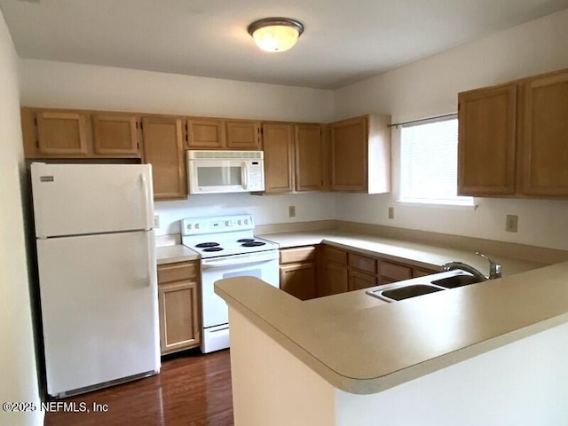 kitchen with white appliances, dark hardwood / wood-style flooring, kitchen peninsula, and sink