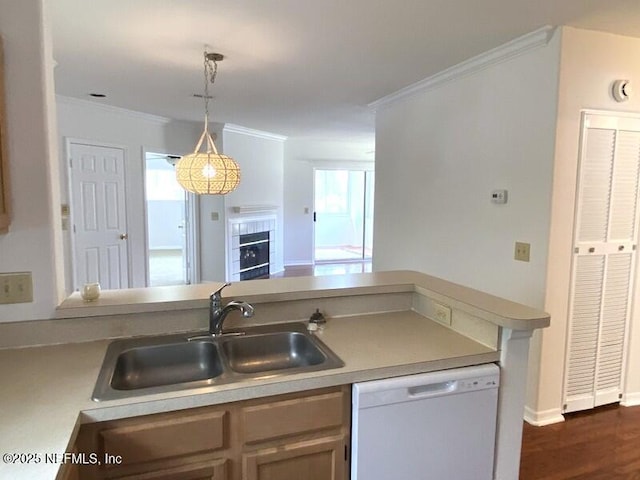 kitchen with pendant lighting, sink, dishwasher, ornamental molding, and a tiled fireplace