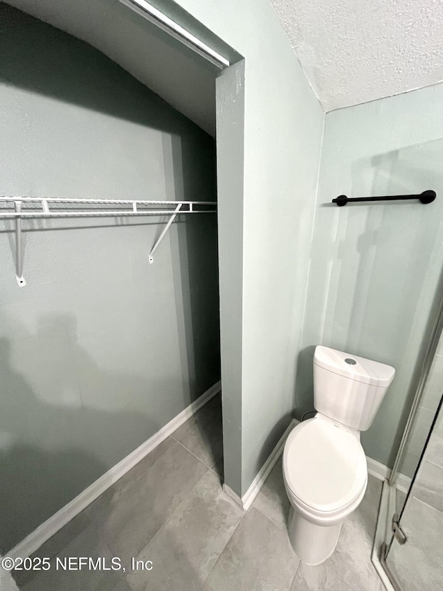 bathroom with toilet, a textured ceiling, and tile patterned floors