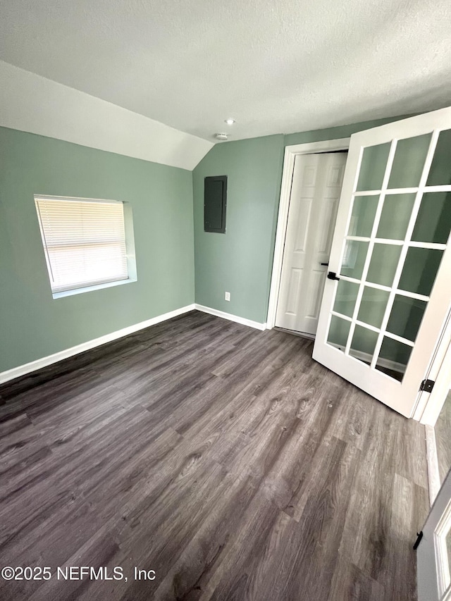 spare room featuring electric panel, vaulted ceiling, hardwood / wood-style floors, and a textured ceiling