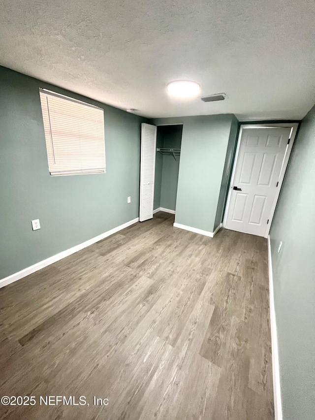 unfurnished bedroom featuring a closet, hardwood / wood-style floors, and a textured ceiling