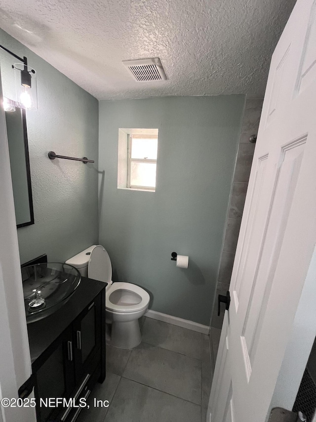 bathroom featuring vanity, toilet, a textured ceiling, and tile patterned flooring