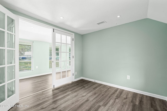 unfurnished room featuring baseboards, visible vents, dark wood finished floors, vaulted ceiling, and french doors