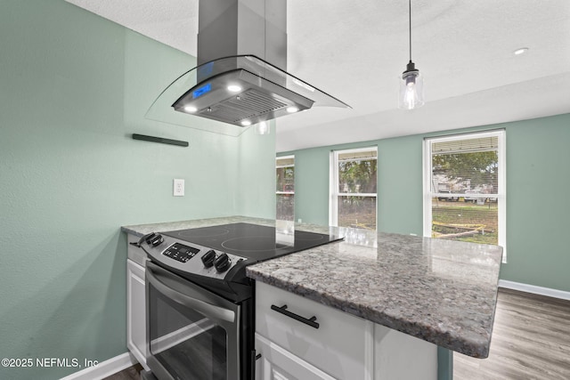 kitchen featuring light wood finished floors, white cabinets, electric stove, decorative light fixtures, and island exhaust hood