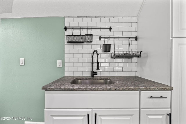 kitchen featuring tasteful backsplash, white cabinetry, and a sink