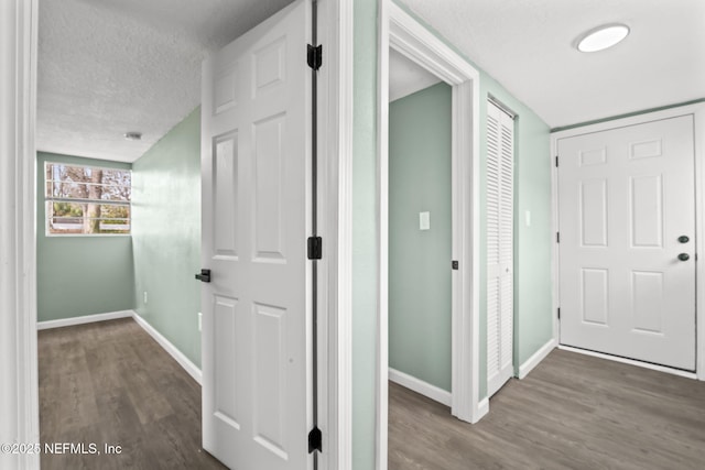 hall featuring baseboards, a textured ceiling, and wood finished floors