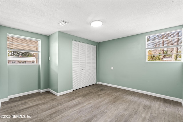 unfurnished bedroom with multiple windows, a closet, and wood finished floors