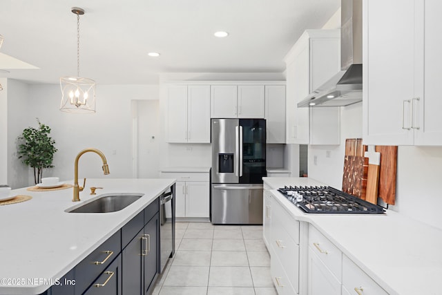 kitchen featuring light countertops, appliances with stainless steel finishes, white cabinets, wall chimney exhaust hood, and a sink